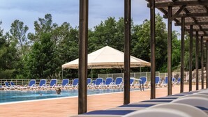 A poolside area with blue lounge chairs and a covered seating area. - Belambra Clubs Montpezat - Le Verdon (Montagnac-Montpezat)