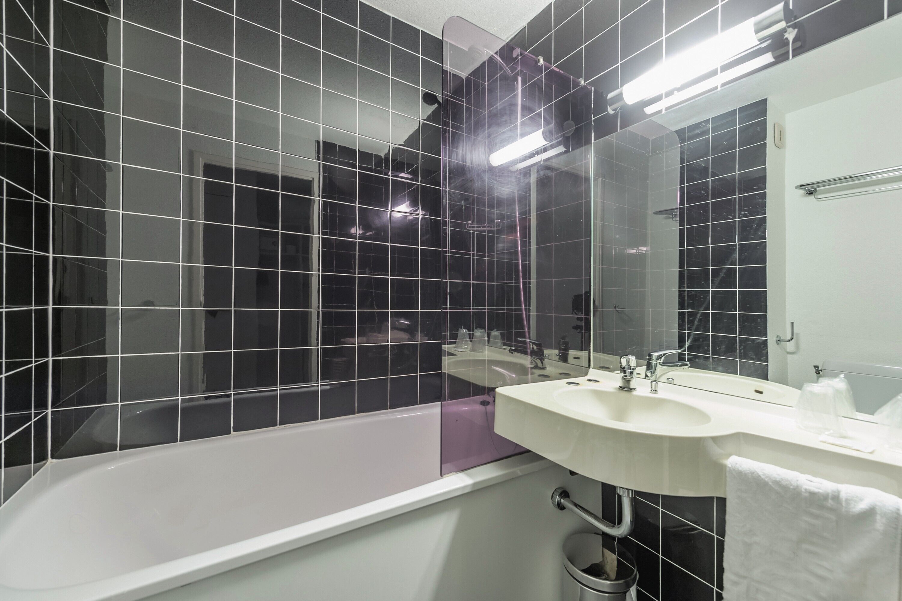 A modern bathroom with a bathtub, a sink, and a large mirror.