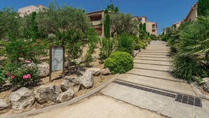 A pathway leading to a building with a stone wall and greenery on one side. - Belambra Clubs Montpezat - Le Verdon (Montagnac-Montpezat)