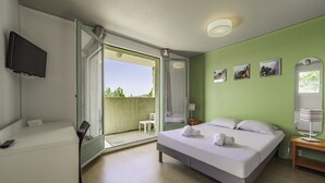 A hotel room with a bed, a desk, a TV, a balcony, and a green wall with pictures. - Belambra Clubs Montpezat - Le Verdon (Montagnac-Montpezat)