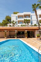 Una piscina al aire libre, sombrillas, sillones reclinables de piscina