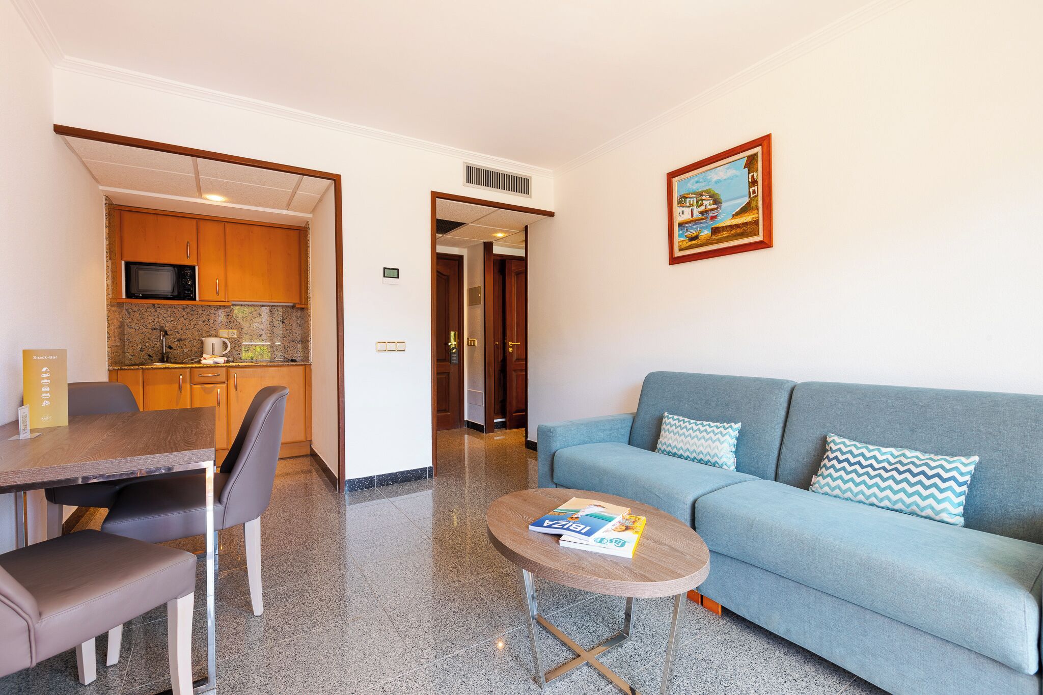 Una sala moderna con sofá, una mesa de centro y un comedor con mesa y sillas.