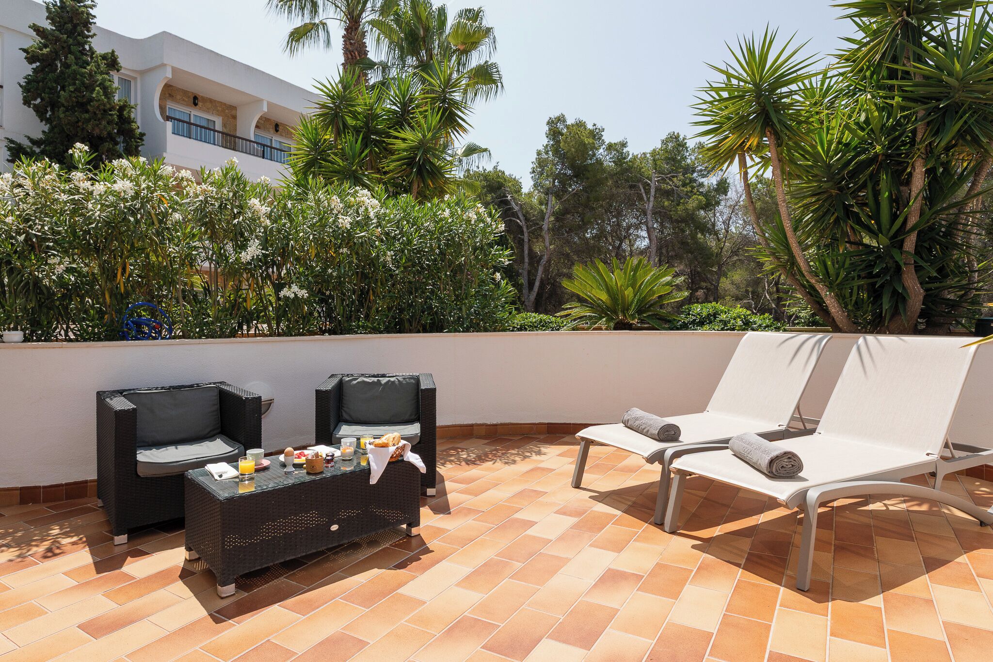 Una terraza en la azotea con mobiliario exterior, una mesa de comedor y abundante vegetación.