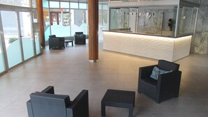 A lobby with seating, a reception desk, and a large window. - Apartamentos Costa d'Or (Calafell)