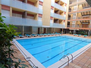 Una piscina al aire libre, sillones reclinables de piscina