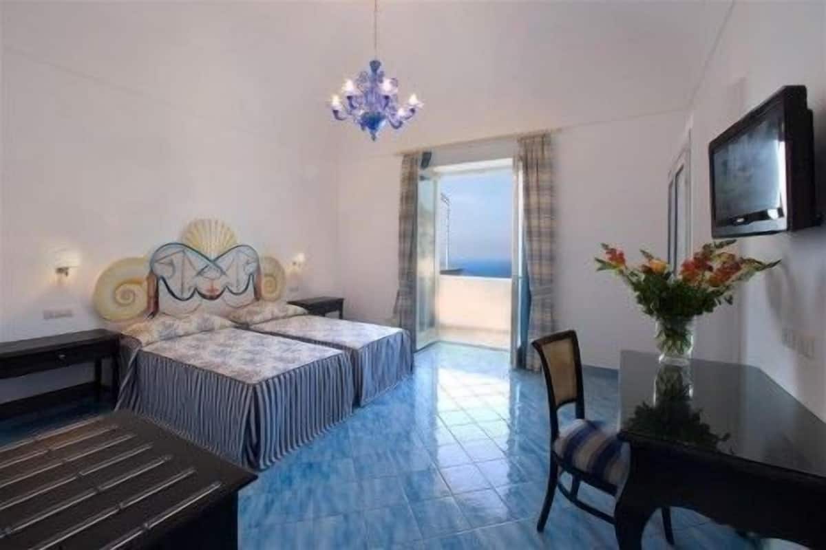 A hotel room with two beds, a TV, a desk, and a chair.