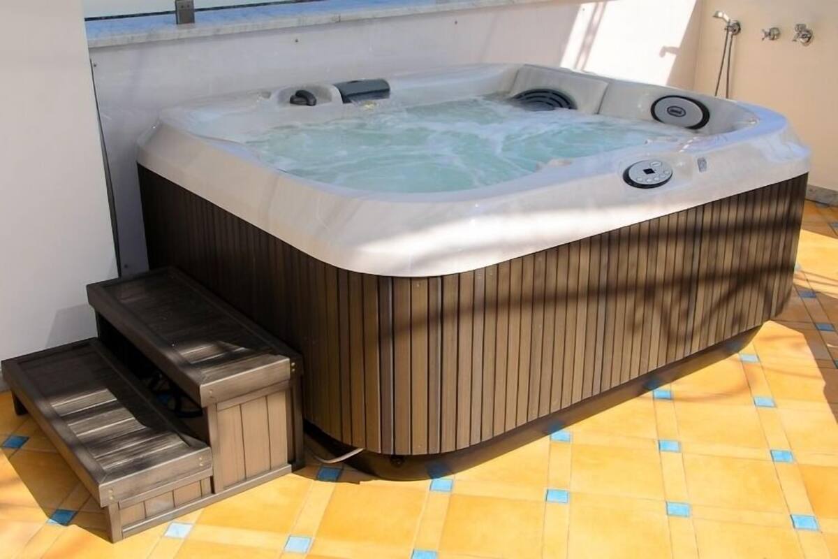 A hot tub with a wooden exterior, a built-in seat, and a step for access.