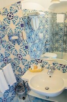 Un baño con lavabo, espejo y azulejos estampados.