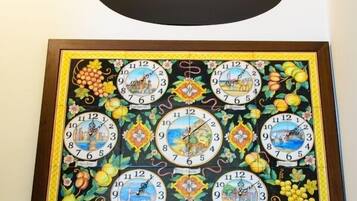 A wall-mounted clock with multiple faces, each depicting different scenes and surrounded by decorative elements.