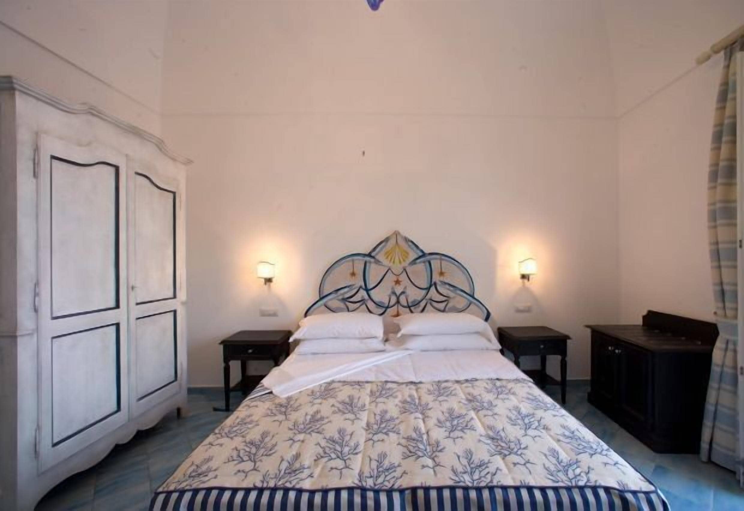 A bedroom with a bed, two bedside tables, a wardrobe, and wall-mounted lamps.