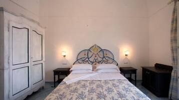 A bedroom with a bed, two bedside tables, a wardrobe, and wall-mounted lamps.