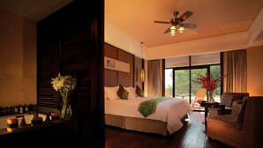 A hotel room with a large bed, a sitting area with a chair, a small table, and a ceiling fan. - Landison Longjing Resort (Hangzhou)