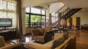 A spacious living room with a large window, a staircase, and a television. - Landison Longjing Resort (Hangzhou)