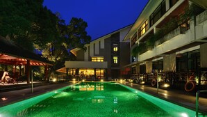A swimming pool with a tiled deck, surrounded by buildings with balconies and outdoor seating. - Landison Longjing Resort (Hangzhou)
