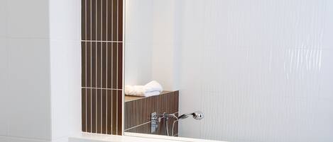 A bathroom with a double sink, a mirror, and a towel rack.
