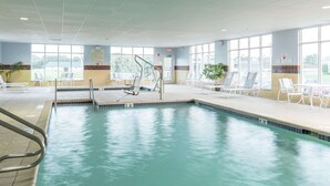 A swimming pool with a tiled deck, sun loungers, and a lifeguard chair.