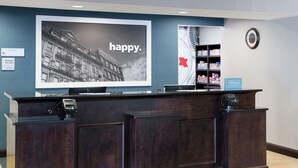 A reception desk with a large digital screen displaying a cityscape and the word "happy."