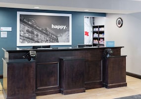 Un mostrador de recepción con una pantalla digital grande que muestra un paisaje urbano y la palabra 'happy'.