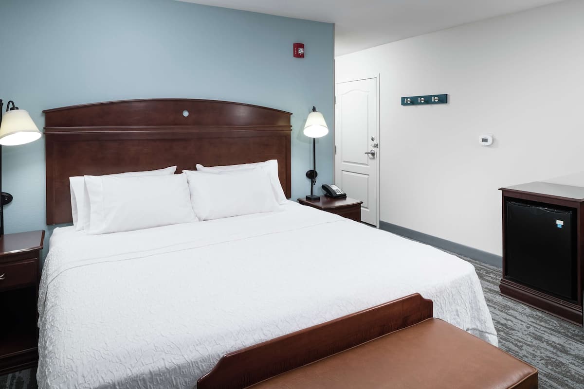 A hotel room with a large bed, bedside lamps, a desk, a chair, and a television.