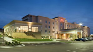 A multi-story hotel with a modern design, featuring a prominent entrance with a covered area and a parking lot in front.