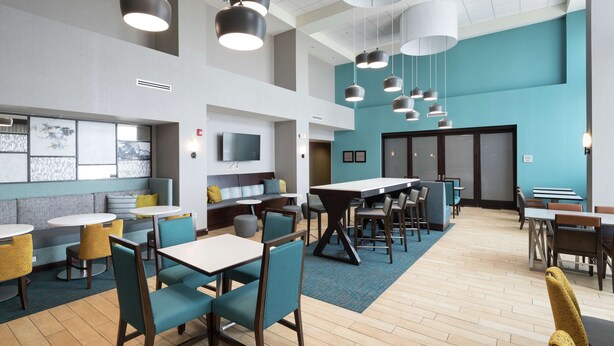 A modern dining area with high tables, chairs, and pendant lighting.