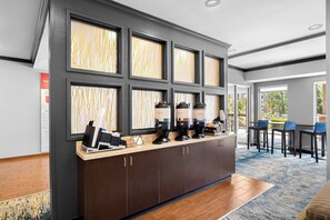 A reception area with a counter, multiple coffee machines, and a seating area with chairs.