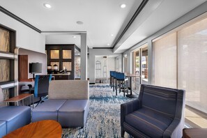 A hotel lobby with seating, a reception desk, and a view of the outdoors.