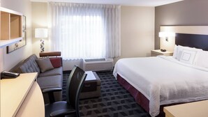 A hotel room with a bed, a desk, a chair, a sofa, a lamp, and a window with curtains. - TownePlace Suites by Marriott Little Rock West (Little Rock)