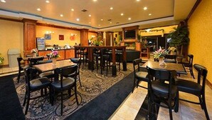 A hotel lobby with a bar area, multiple seating arrangements, and a reception desk.