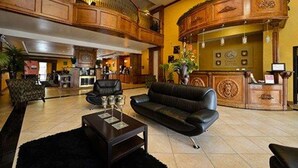 A lobby with a black leather sofa, a wooden reception desk, and a chandelier.