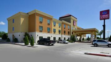 A hotel with a yellow facade, a covered entrance, and a sign for Comfort Suites.