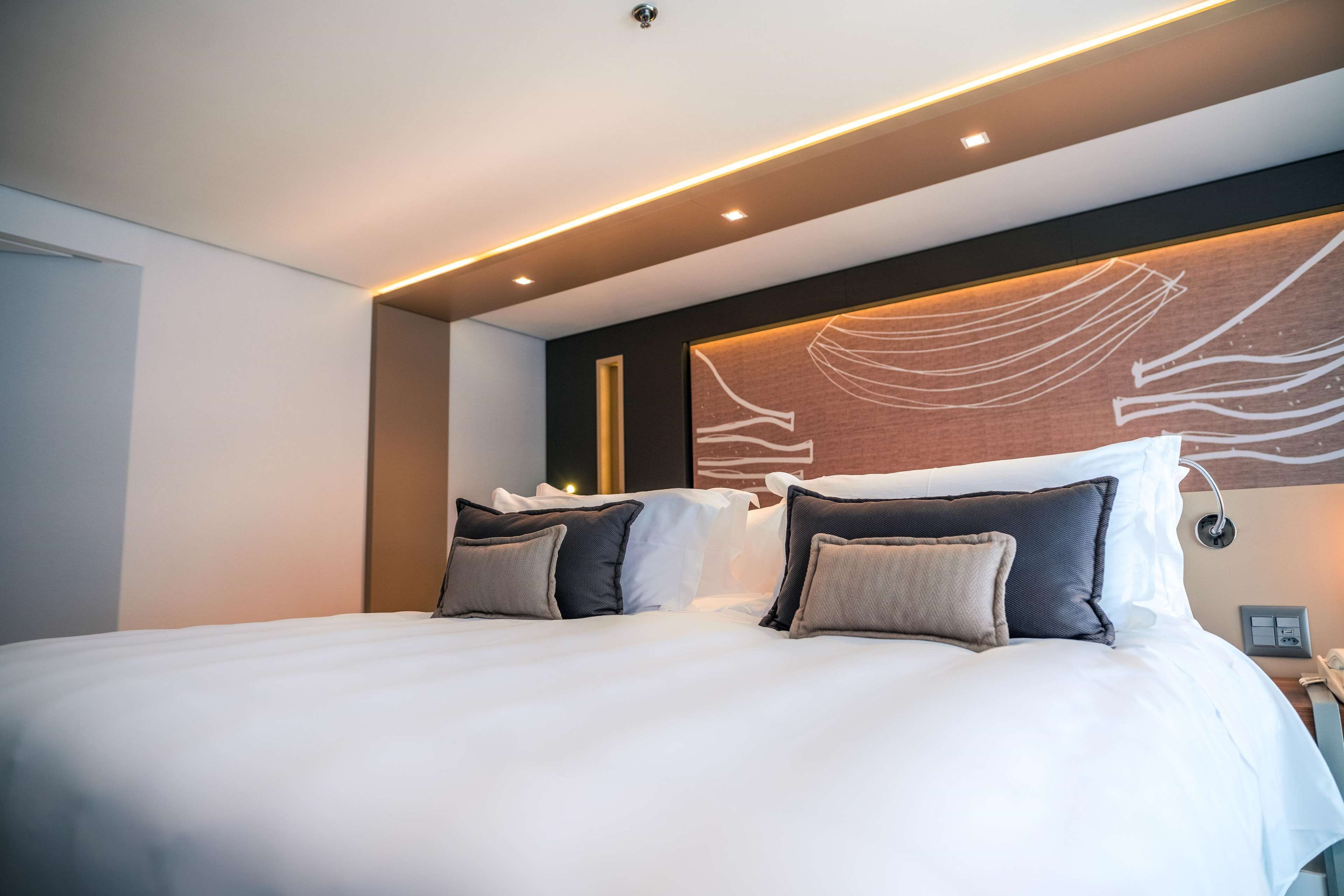 Una habitación de hotel moderna con una cama grande, dos mesitas de noche y una obra de arte colgada en la pared.