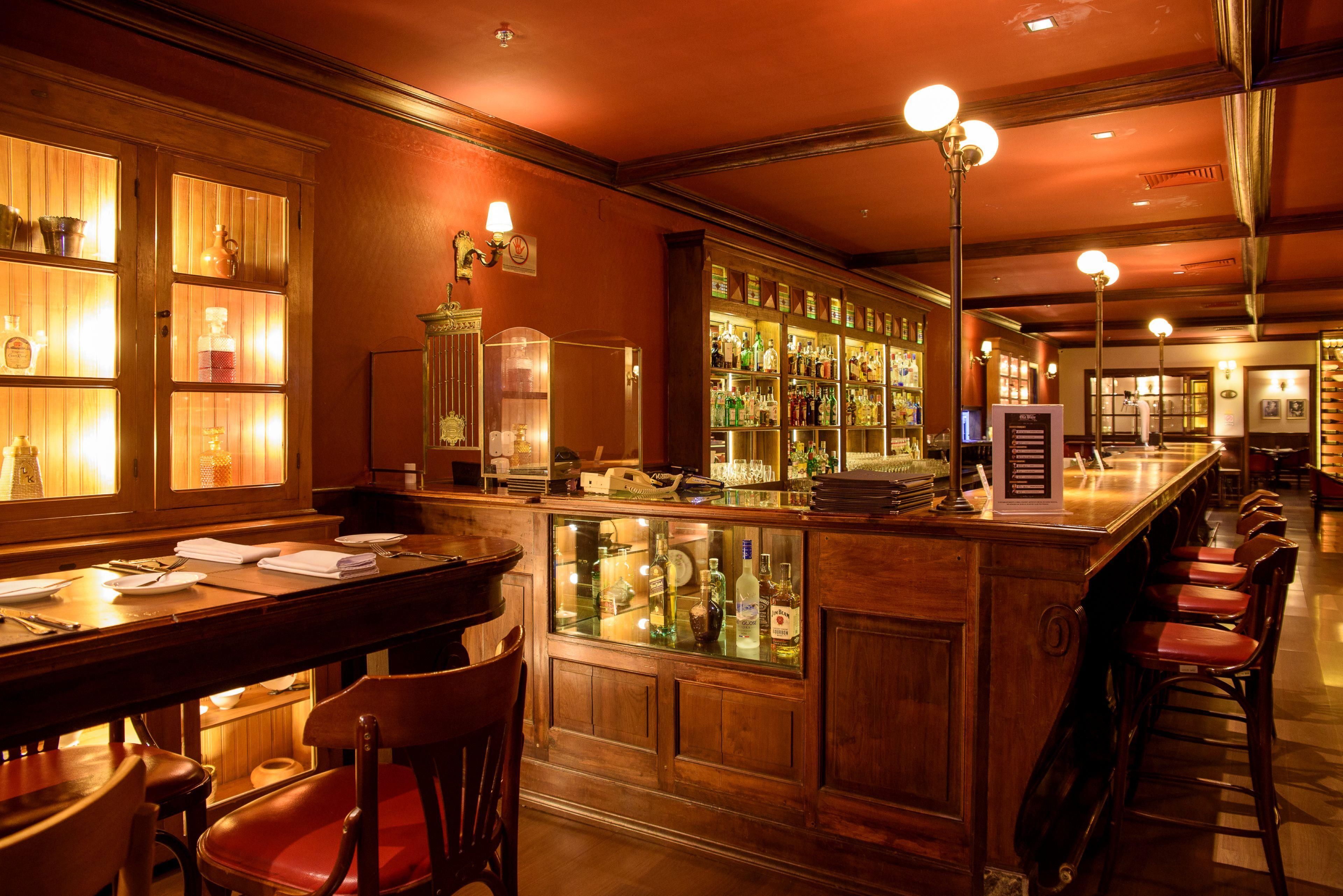 A bar area with wooden furnishings, a glass display case with bottles, and a menu stand.