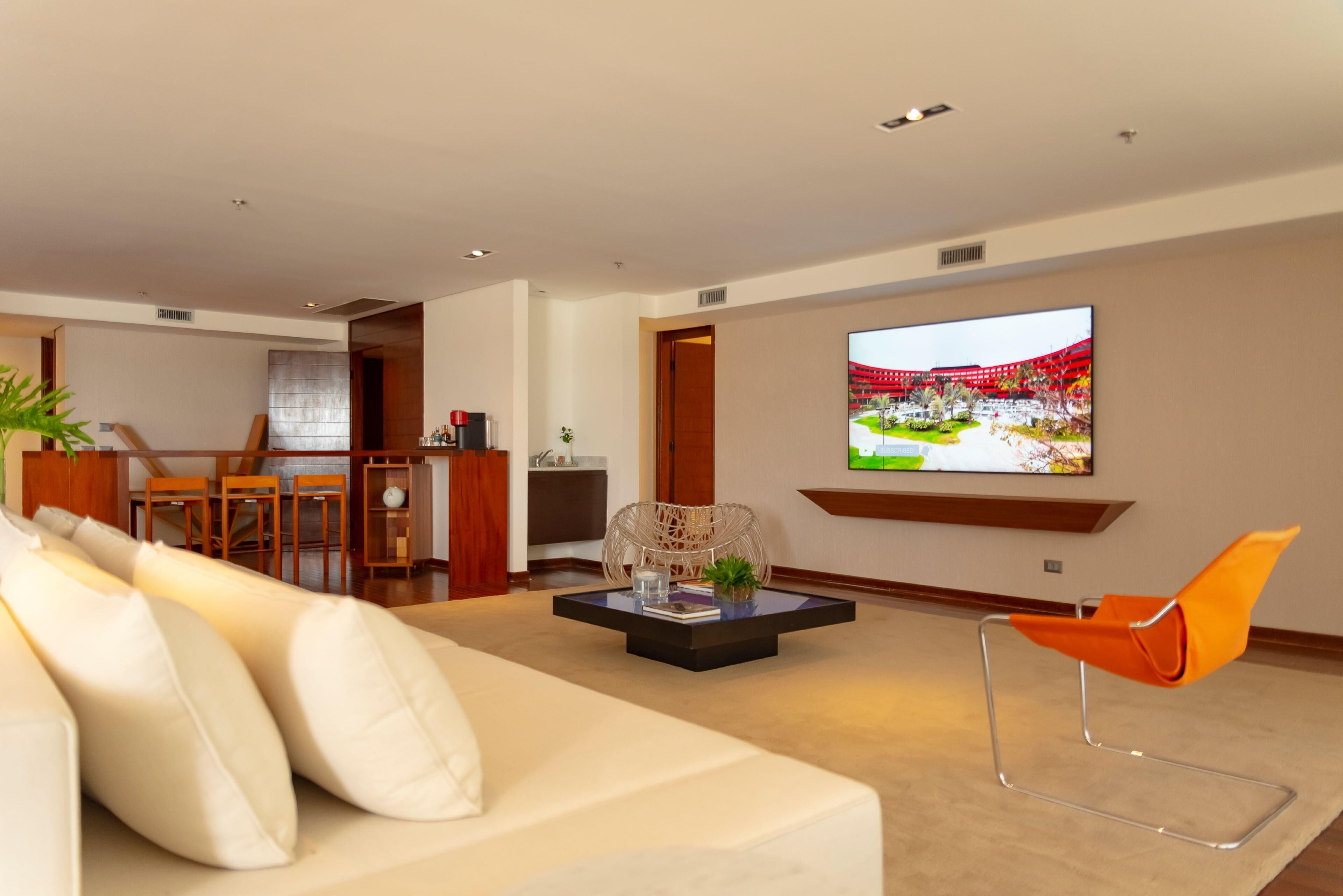 Uma sala de estar moderna com um sofá, uma mesa de centro e uma TV fixada na parede.