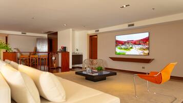 Uma sala de estar moderna com um sofá, uma mesa de centro e uma TV fixada na parede.