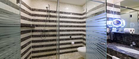 A modern bathroom with a glass-enclosed shower, a marble-tiled floor, and a vanity with a sink and mirror.