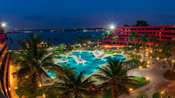 Un hotel con una gran piscina rodeada de palmeras y vistas al mar.