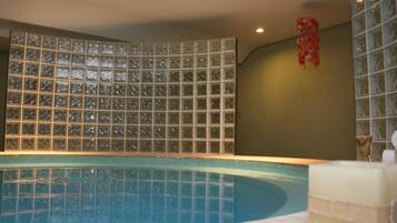 Relax by the pool, surrounded by a sleek, rectangular pool with a curved edge and a stylish tile backdrop.