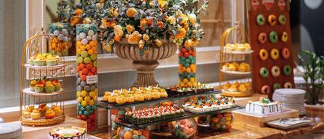 Una mesa de buffet con diversos postres, un centro de mesa floral y una exhibición de rosquillas.