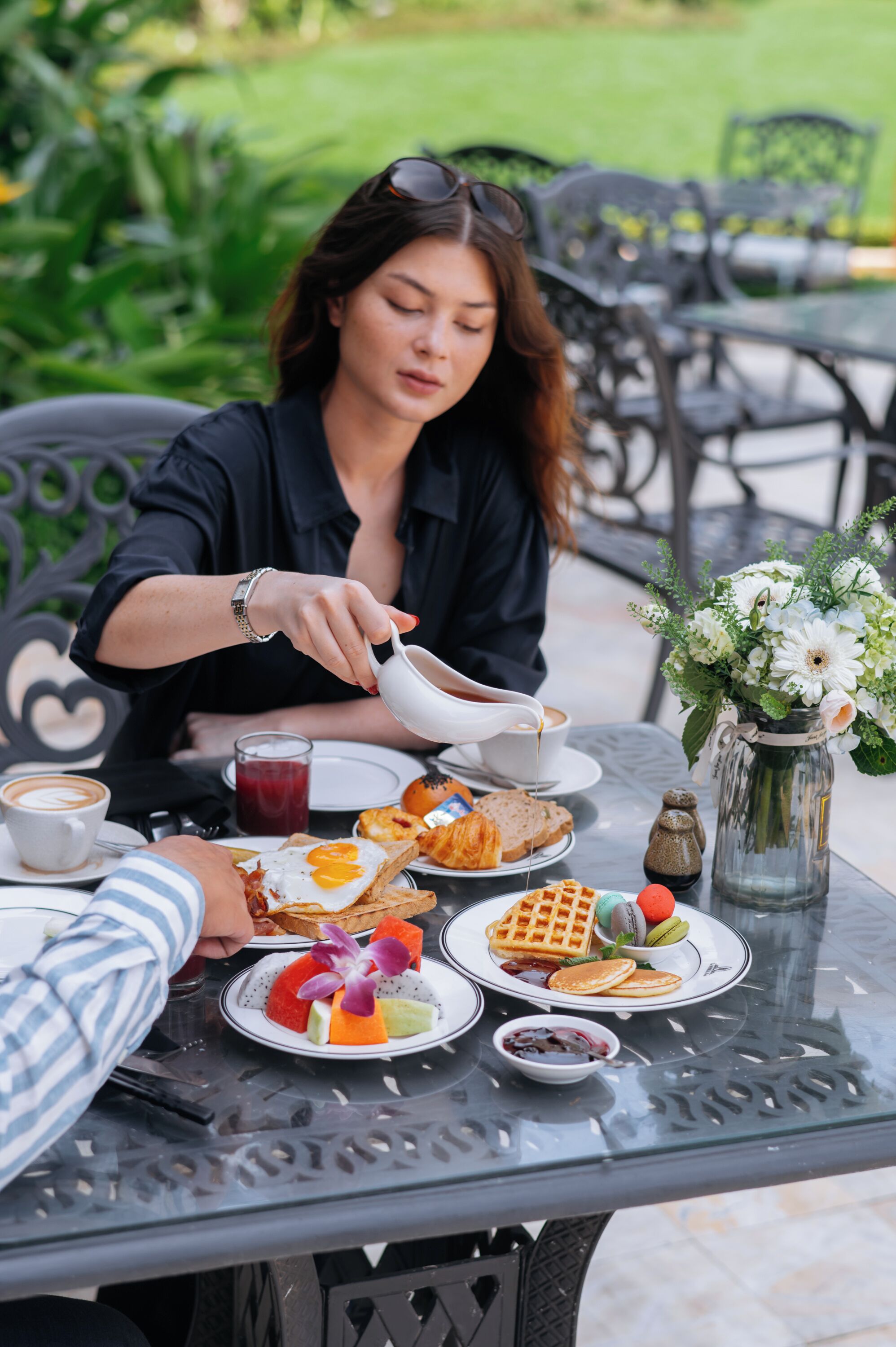 A dining table with various breakfast items, including waffles, pancakes, and fruit.