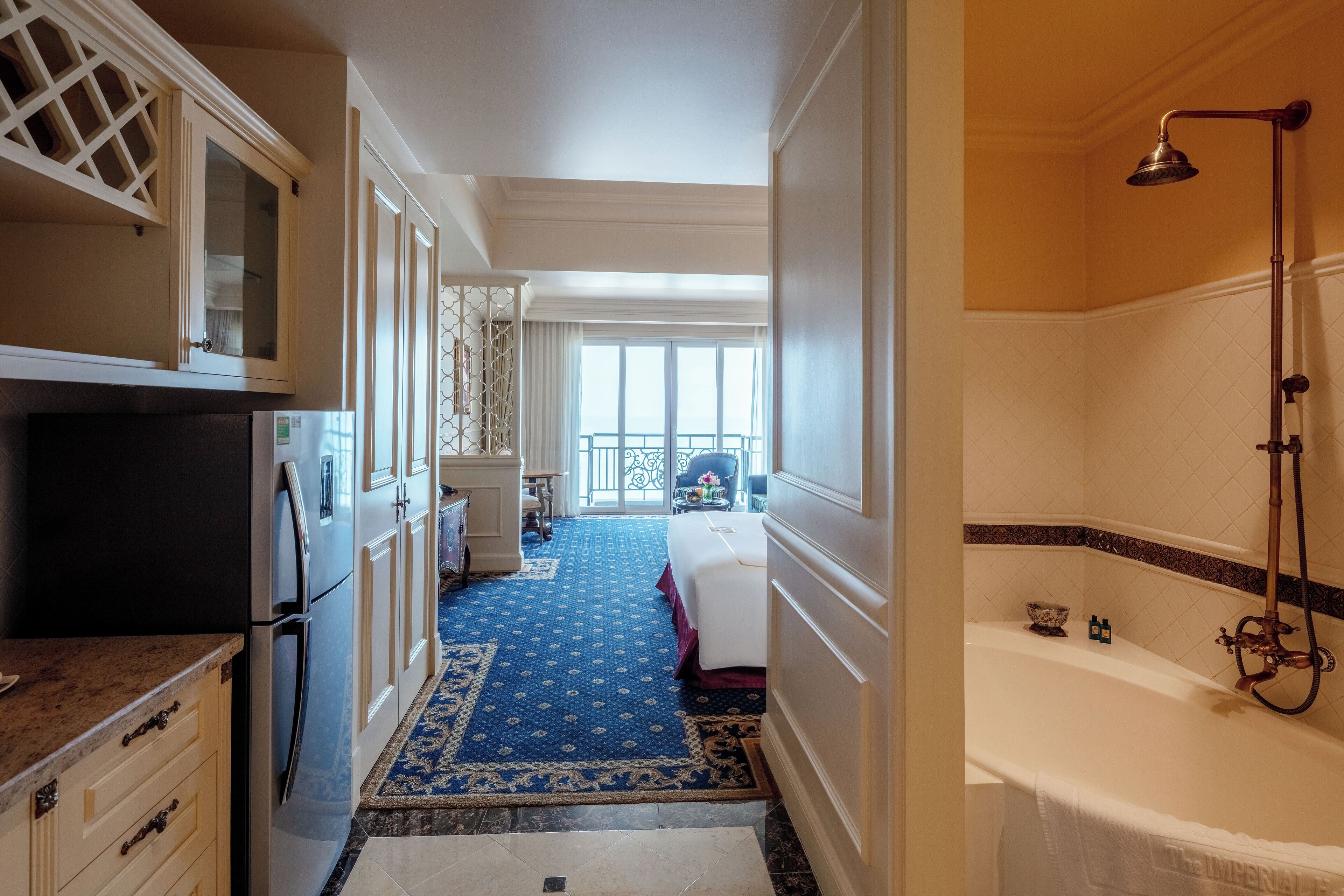 A hotel room with a large bed, a bathroom with a bathtub, and a kitchen area.