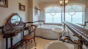 Un baño clásico con una bañera independiente, un tocador con espejo y una ventana con vistas.