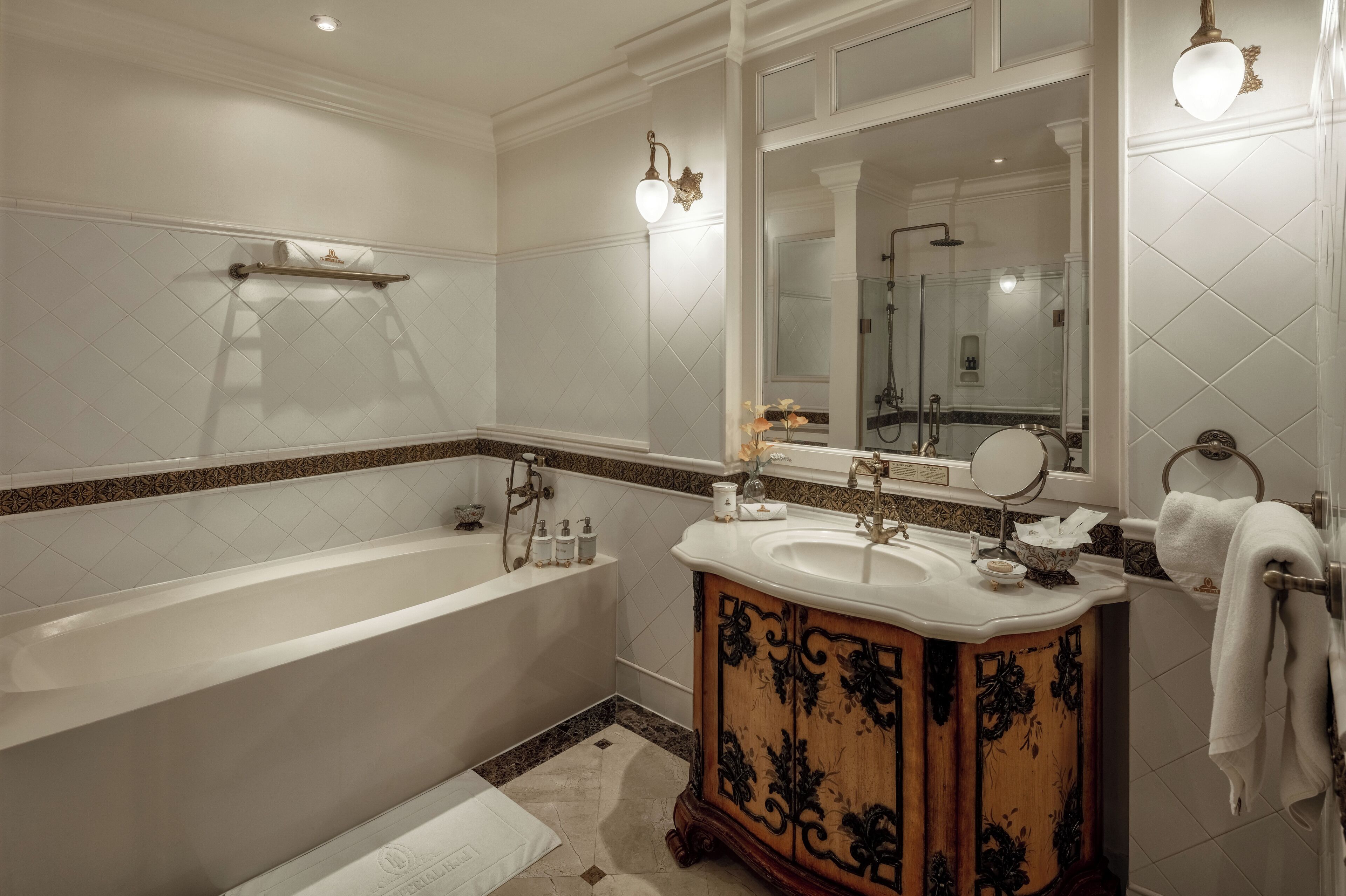 Une salle de bain classique avec une baignoire sur pieds, un meuble-lavabo en bois avec un miroir et un grand miroir au-dessus du lavabo.