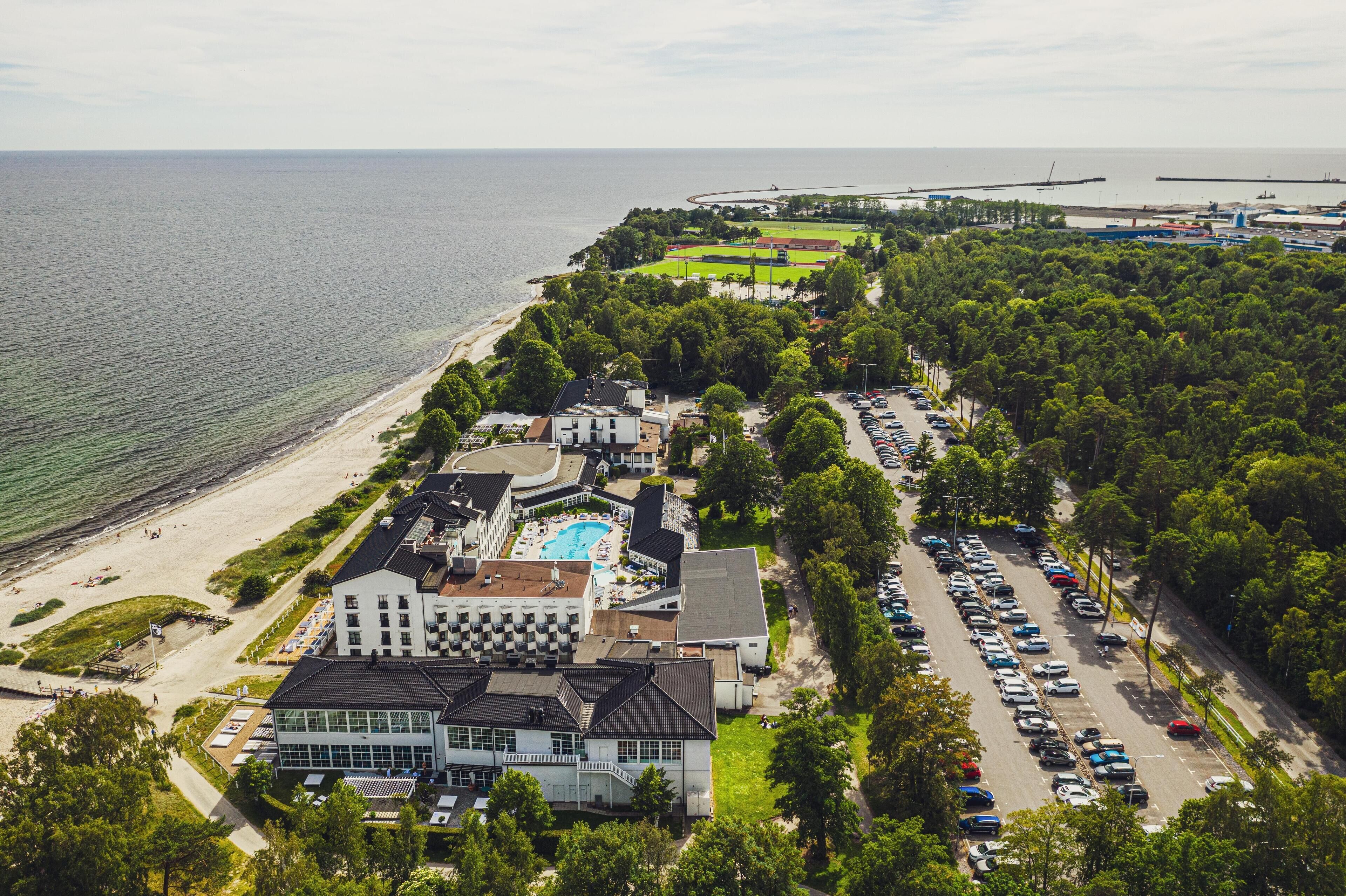 Ilmakuva rannikolla sijaitsevasta hotellista, jossa on uima-allas, parkkipaikka ja pääsy rannalle.