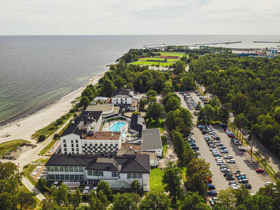 Ilmakuva rannikolla sijaitsevasta hotellista, jossa on uima-allas, parkkipaikka ja pääsy rannalle.
