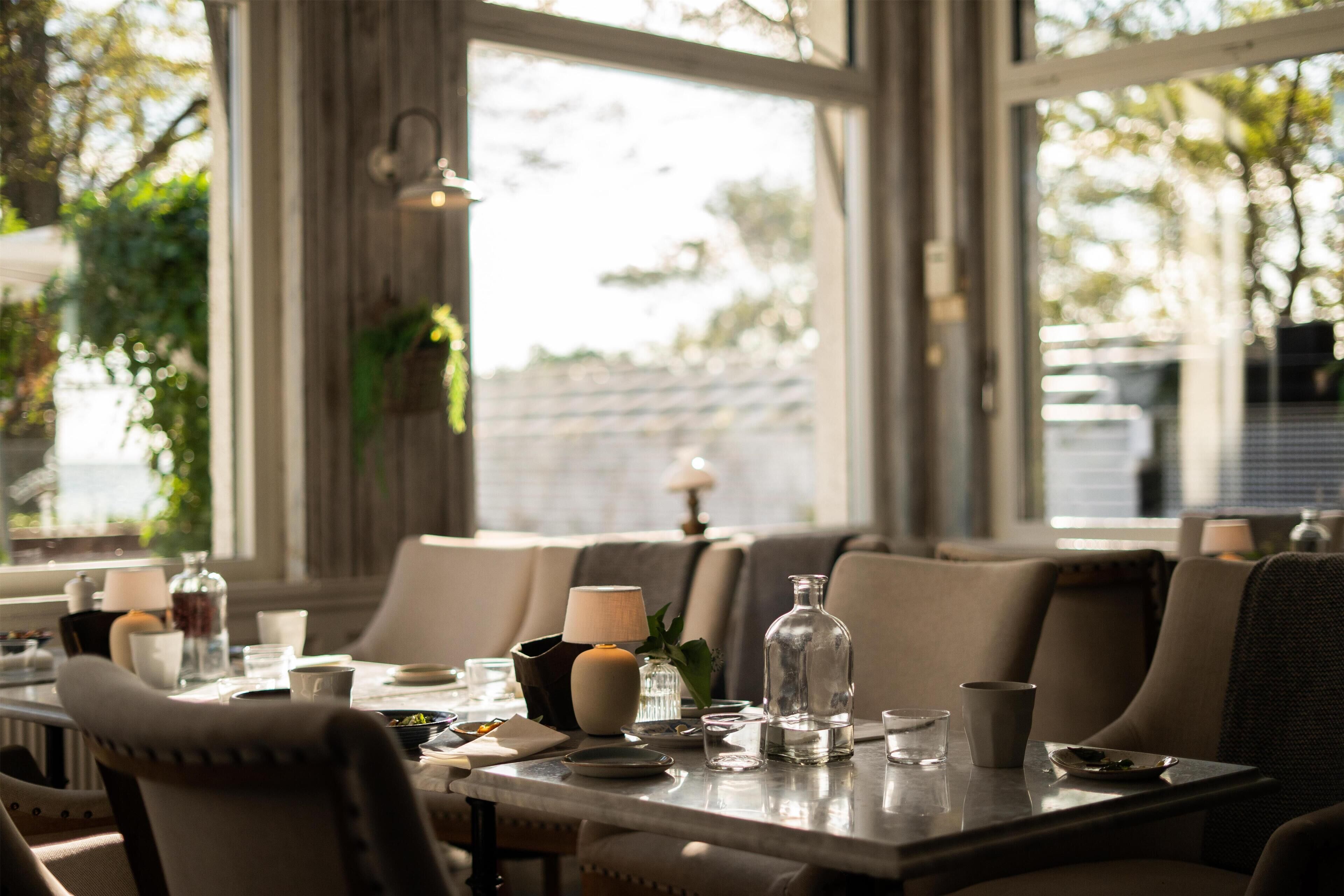 A dining area with a table set for two, featuring a candle, a glass, and a pitcher.