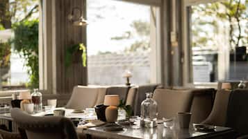 A dining area with a table set for two, featuring a candle, a glass, and a pitcher.