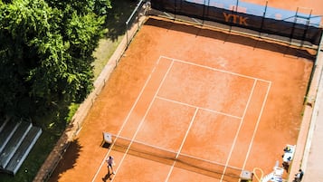 Vista aérea de una cancha de tenis con jugadores, una red y una valla.