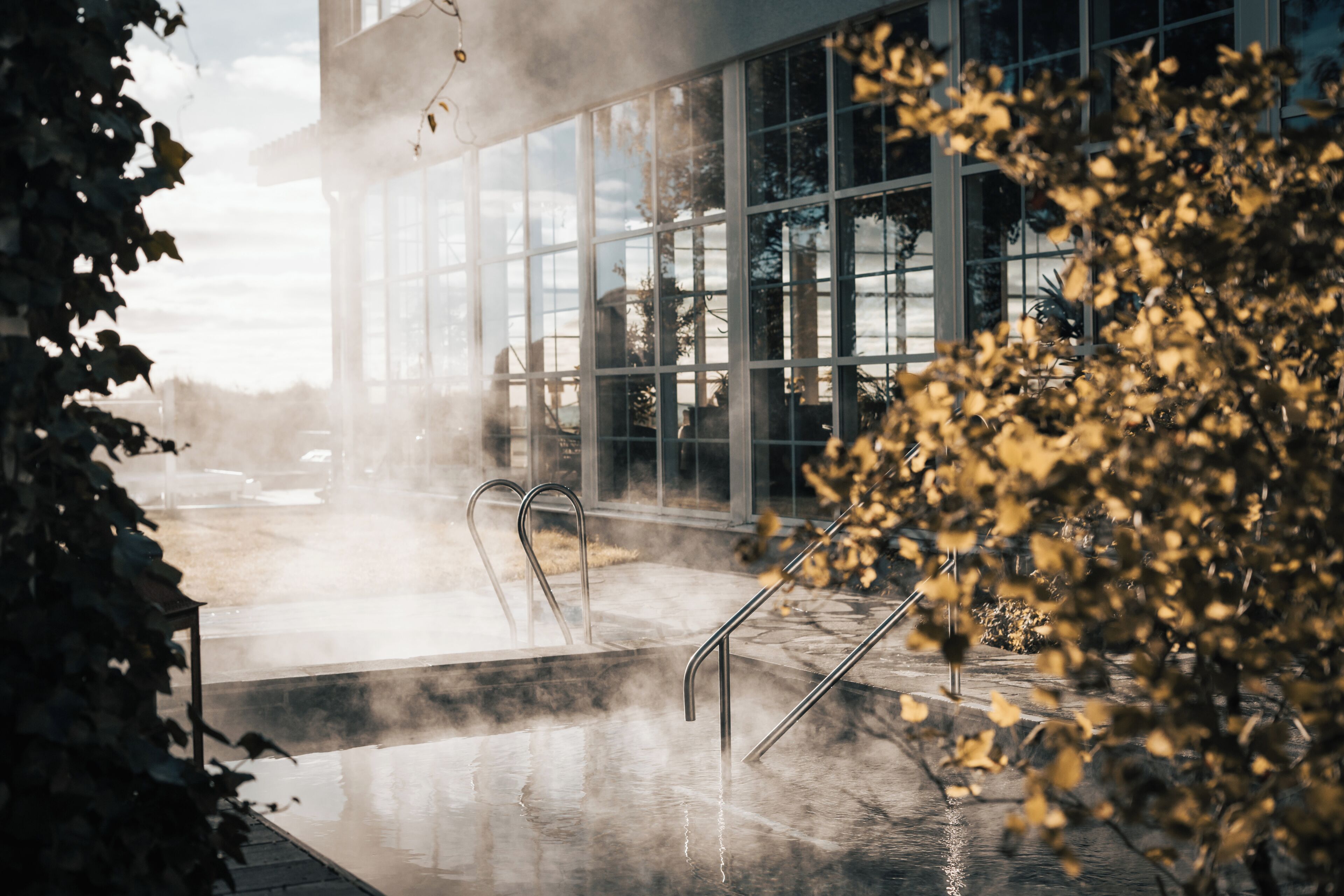 Un baño de vapor con barandillas metálicas y un edificio de vidrio al fondo.