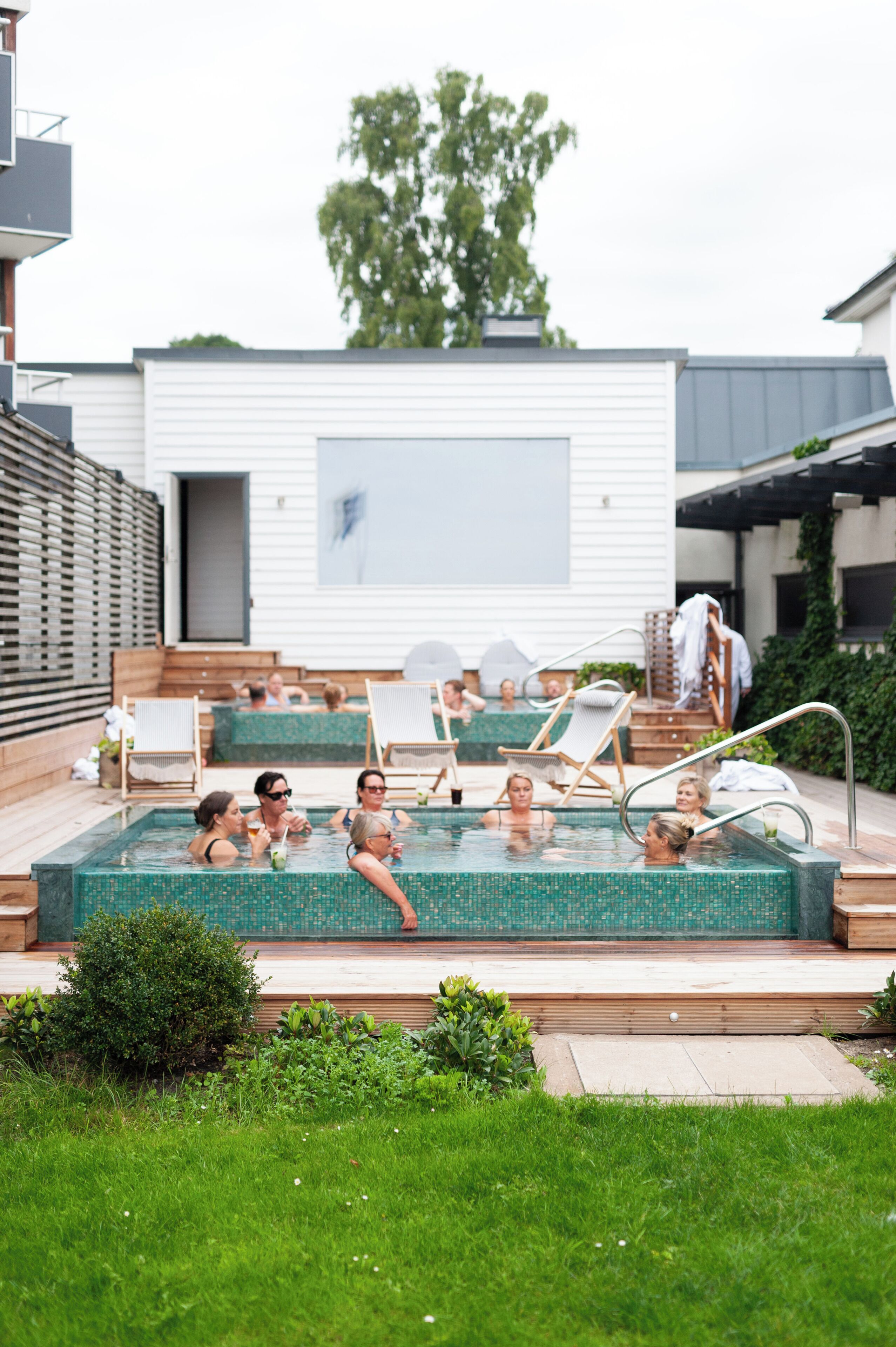 A swimming pool area with multiple lounge chairs and a wooden deck.